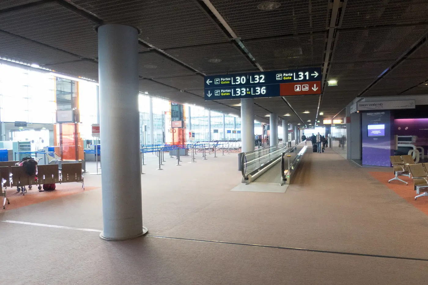 Hall L of Terminal 2 at Paris-Charles de Gaulle airport, with boarding gate signs and a moving walkway.