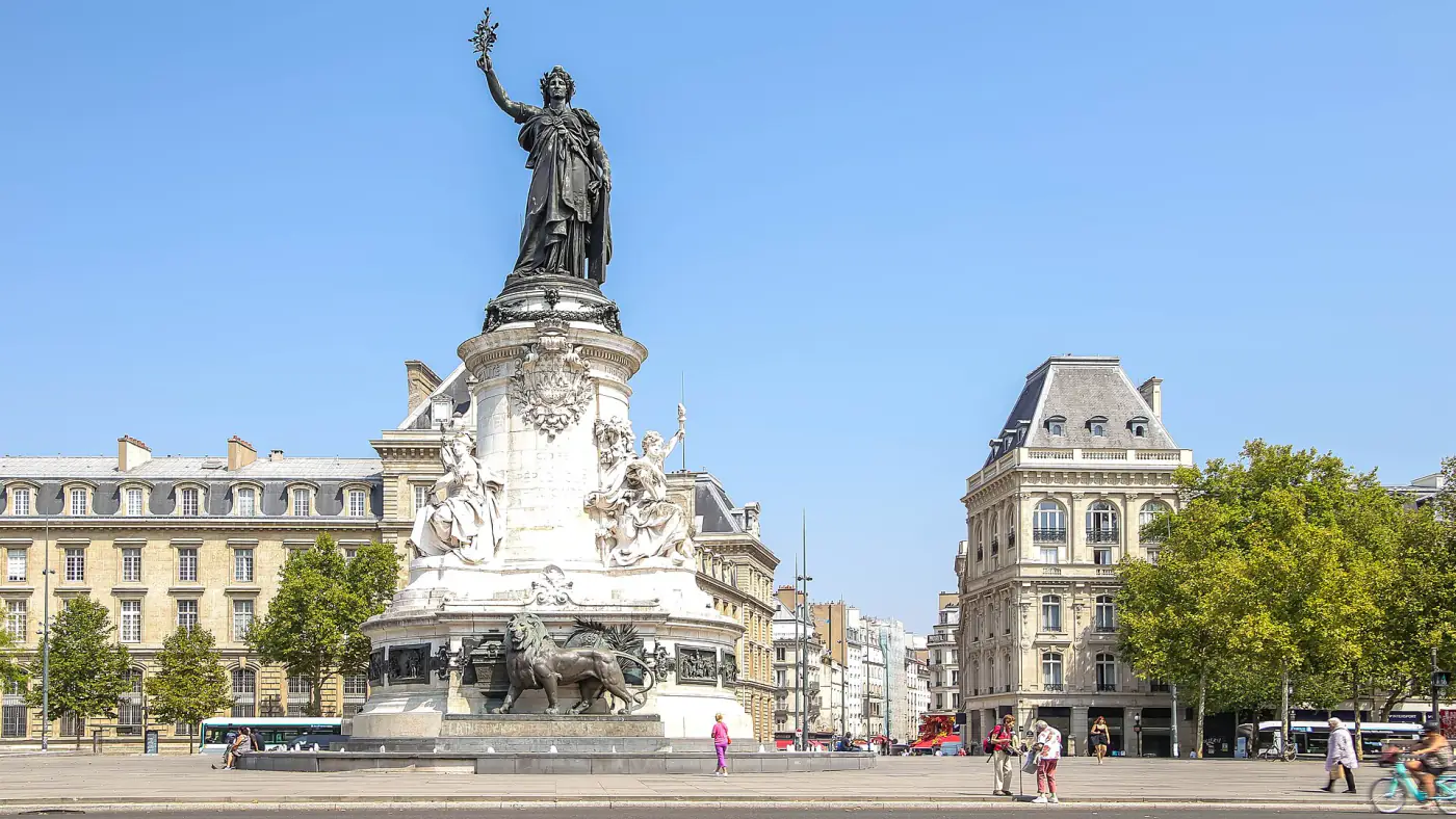 Monument to the Republic on Place de la République in Paris, seen from the front on a clear day, with Haussmann buildings around the square.
