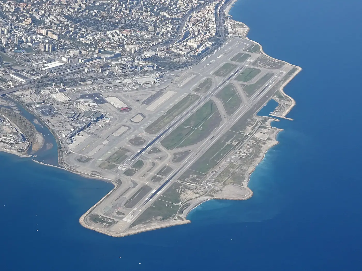 Vue aérienne de l'aéroport Nice Côte d'Azur, ses pistes sur la mer et la ville de Nice